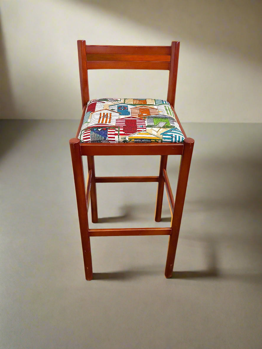 Wooden bar stool with a colorful cushion on a plain background