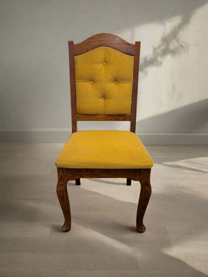 Wooden chair with yellow cushioned seat and backrest on a plain background