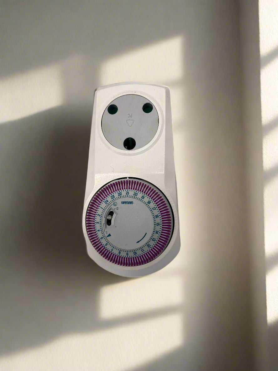 White wall-mounted timer with a circular dial on a light-colored wall.