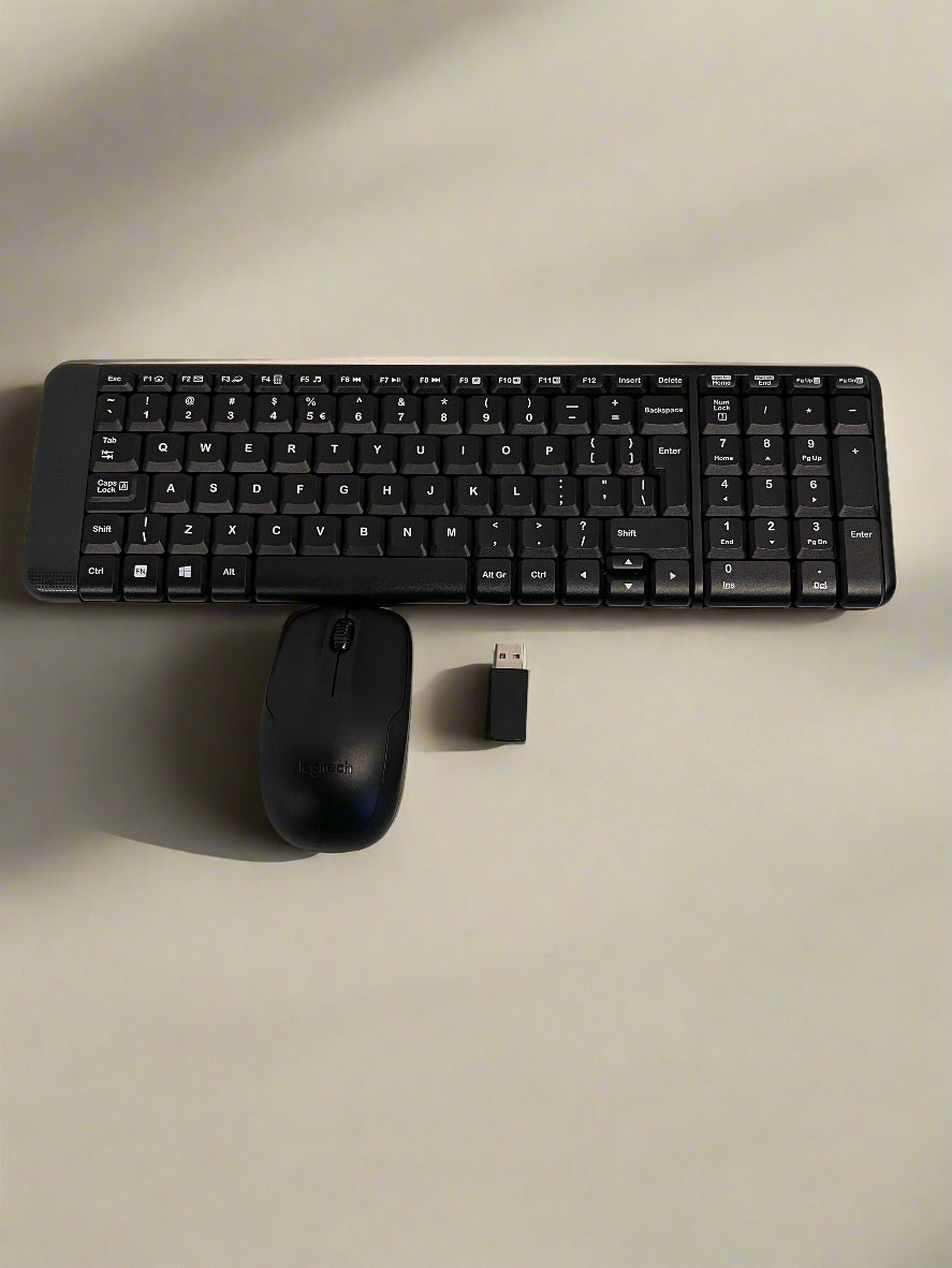 Black keyboard, mouse, and USB receiver on a light gray surface
