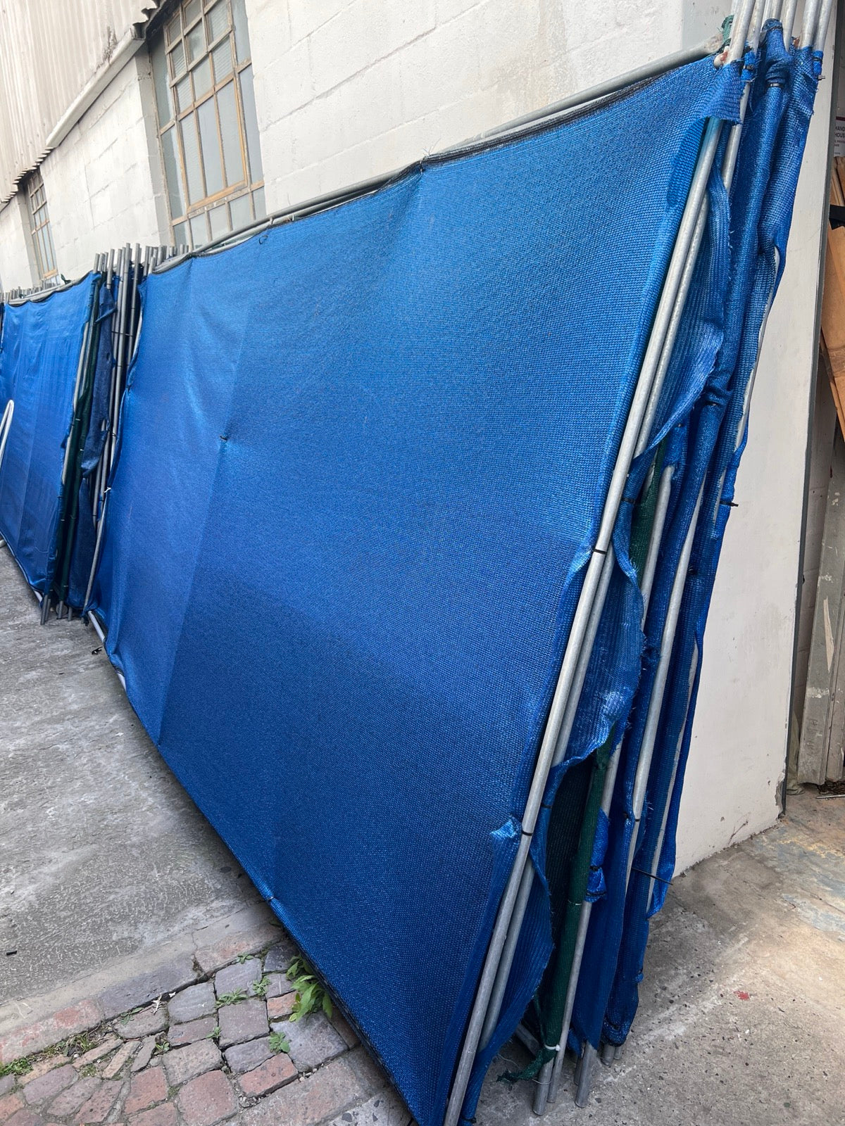 Blue shade-cloth fence divider panels stacked